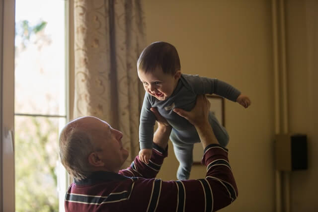 Grandparent holding child up in the air smiling